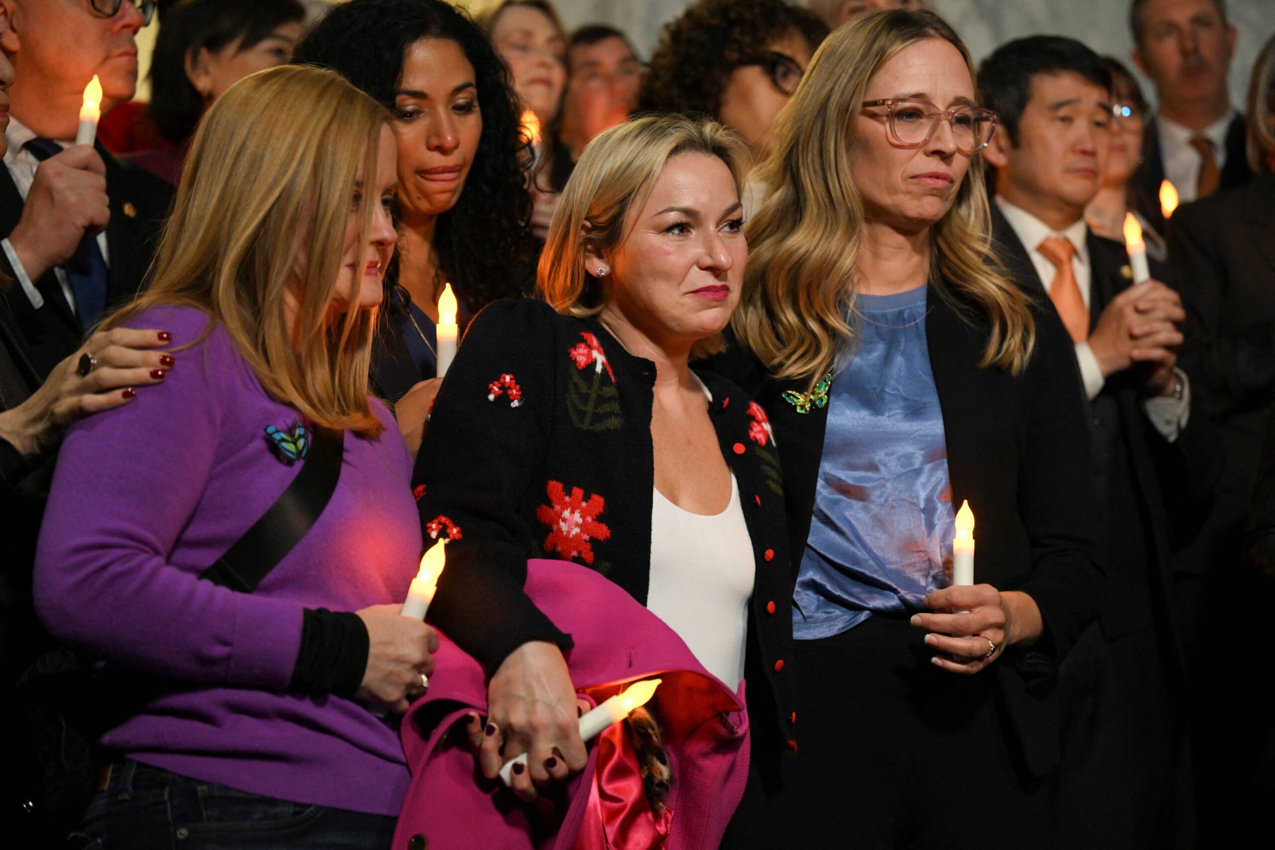 Jeffrey Epstein survivors Liz Stein (left) and Danielle Bensky (center) hold electric candles as they react to the Senate's passing of the bill to force the release of files related to Epstein