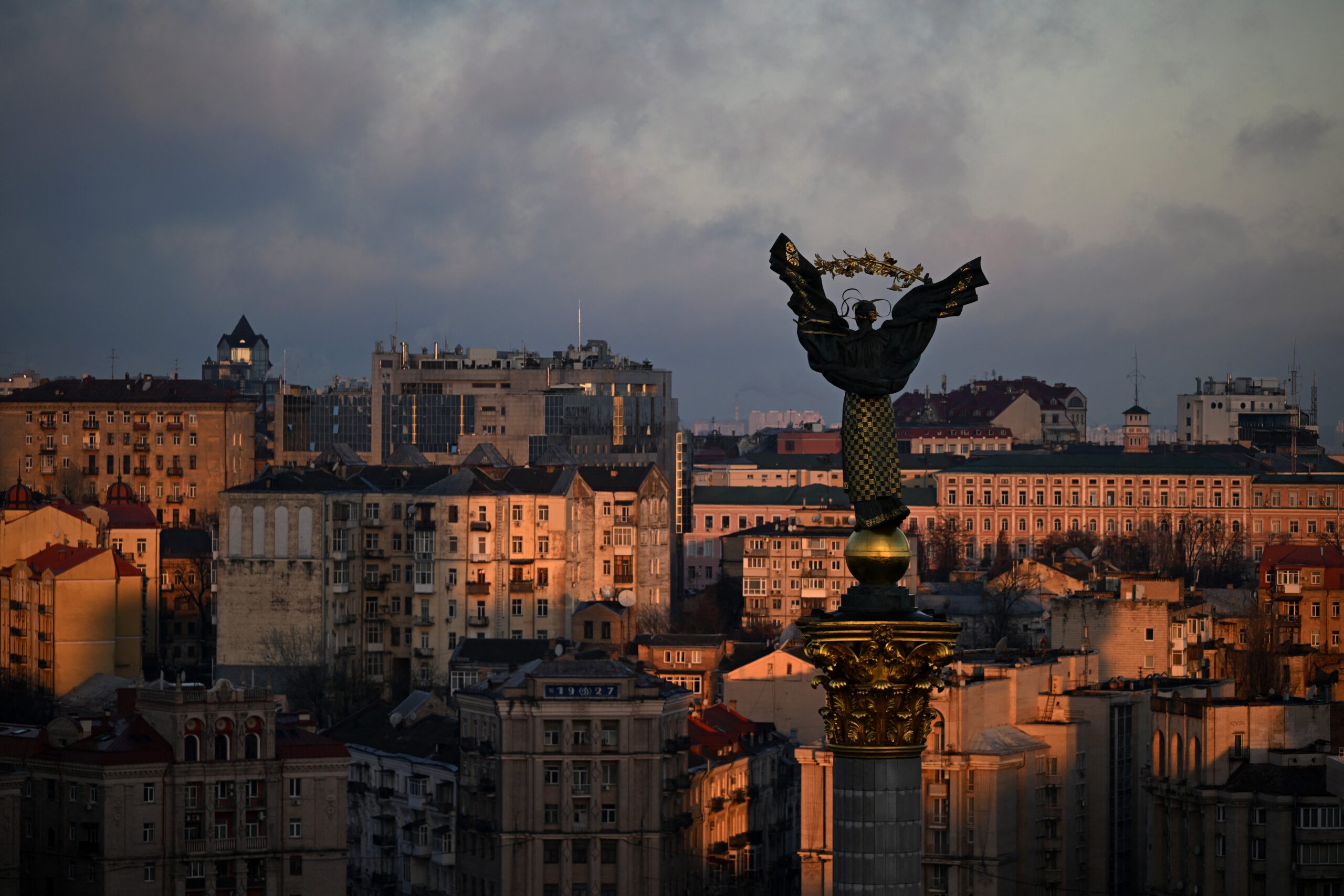 A photograph taken on 24 2025 shows The Independence Monument towers over Independence Square as buildings in the background are illuminated by a beam of sunlight during sunrise in Kyiv