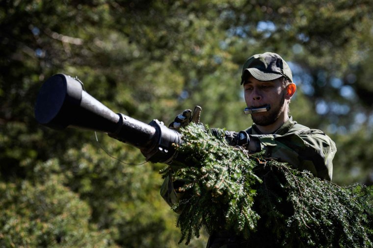 A soldier of the P18 Gotland Regiment of the Swedish Army camouflages an armoured vehicle during a field exercise near Visby on the Swedish island of Gotland on May 17, 2022. - Finland and Sweden are expected to announce this week whether to apply to join NATO following Russia's Ukraine invasion, in what would be a stunning reversal of decades-long non-alignment policies. On Sweden's strategically-located Baltic Sea island of Gotland, Home Guard troops were last week called in for a special month-long training exercise, coinciding with annual military exercises taking place across Finland and Sweden next week. (Photo by Jonathan NACKSTRAND / AFP) (Photo by JONATHAN NACKSTRAND/AFP via Getty Images)