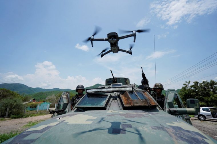 Members of the Jalisco New Generation Cartel (CJNG) pose for a photo as a drone overflies an armoured vehicle at an undisclosed location, in Michoacan state, Mexico, July 1, 2021. REUTERS/Stringer NO RESALES. NO ARCHIVES To match Special Report MEXICO-USA/GUNS