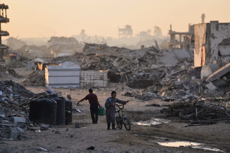 Palestinians walk trough the destruction caused by the Israeli air and ground offensive in Sheikh Radwan neighborhood in Gaza City, Wednesday, Oct. 22, 2025. (AP Photo/Abdel Kareem Hana)