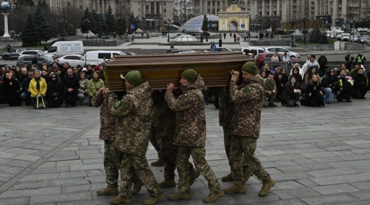 Friends and colleagues kneel as servicemen from a guard of honour carry the coffin of late Ukrainian serviceman Kostiantyn Guzenko, 28, during farewel ceremony in central Kyiv on November 7, 2025, amid the Russian invasion of Ukraine. Kostiantyn Guzenko was a famous Ukrainian art and documentary photographer, who joined the army in early 2024 and was serving as a staff sergeant with the press service of the 35th Separate Marine Brigade. (Photo by Genya SAVILOV / AFP) (Photo by GENYA SAVILOV/AFP via Getty Images)