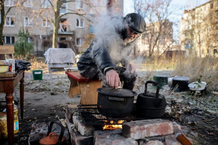 A resident prepares food over a fire, near his apartment building damaged by a Russian military strike, amid Russia's attack on Ukraine, in the frontline town of Kostiantynivka in Donetsk region, Ukraine November 15, 2025. Oleg Petrasiuk/Press Service of the 24th King Danylo Separate Mechanized Brigade of the Ukrainian Armed Forces/Handout via REUTERS ATTENTION EDITORS - THIS IMAGE HAS BEEN SUPPLIED BY A THIRD PARTY.