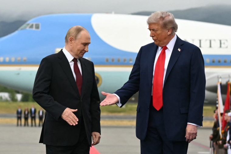 US President Donald Trump (R) reaches out to shake hands with Russian President Vladimir Putin as they pose on a podium on the tarmac after arrival at Joint Base Elmendorf-Richardson in Anchorage, Alaska, on August 15, 2025. Putin is in Alaska at the invitation of Trump in his first visit to a Western country since he ordered the 2022 invasion of Ukraine that has killed tens of thousands of people. (Photo by ANDREW CABALLERO-REYNOLDS / AFP) (Photo by ANDREW CABALLERO-REYNOLDS/AFP via Getty Images)