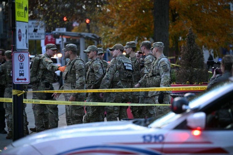 National Guard soldiers stand behind the crime scene tape at a corner in downtown Washington, DC, on November 26, 2025. Two National Guard soldiers were shot a few blocks from the White House, according to law enforcement. (Photo by Drew ANGERER / AFP via Getty Images)