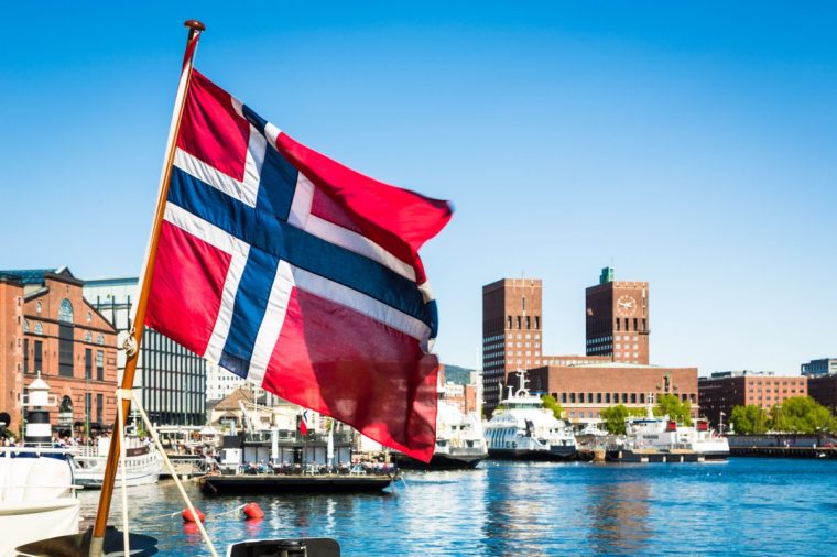 Norwegian flag in front of the city hall building in Oslo, Norway capital city during a sunny summer day.