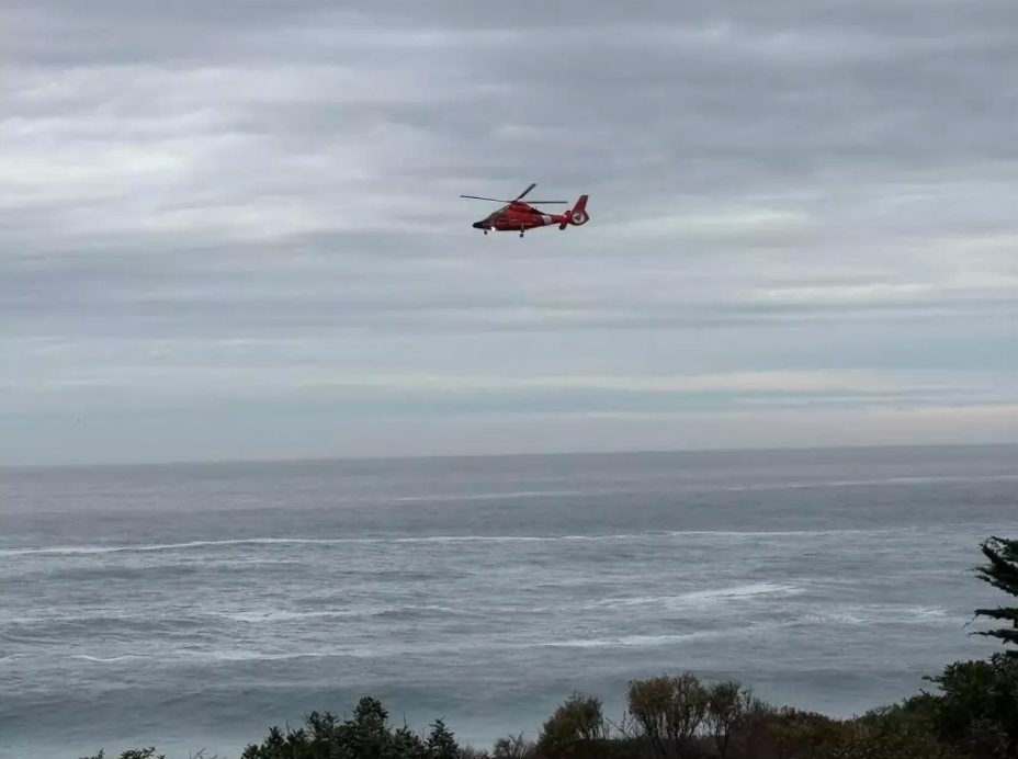 A U.S. Coast Guard helicopter searches the waters near Big Sur, California, for a 7-year-old girl who was swept into the ocean by a wave on Friday, November 14, 2025. The girl's father, Yuji Hu, of Calgary, Canada, died trying to save her.