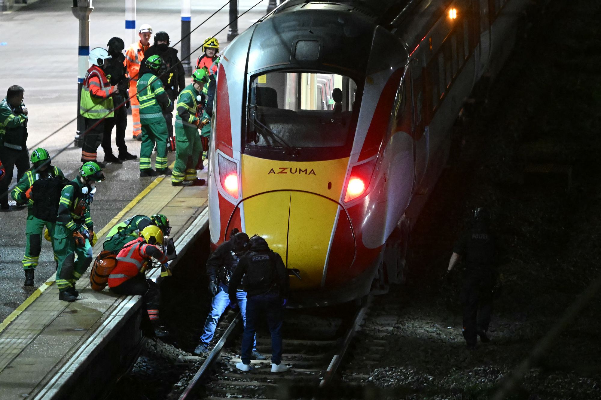 Police officers and members of the emergency services search the track beneath an LNER train at Huntingdon Station