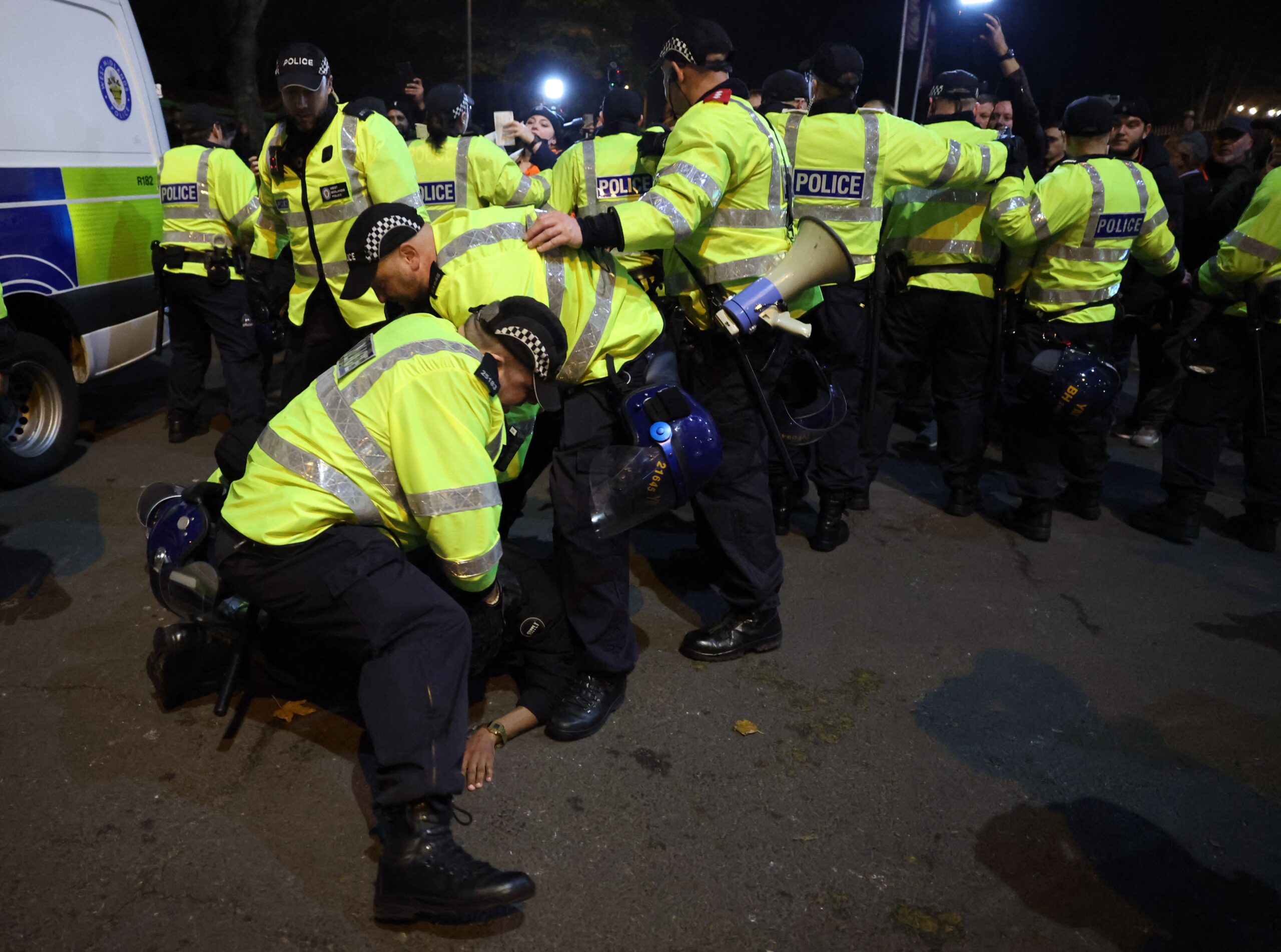 Police officers detain a protester outside the stadium during the match