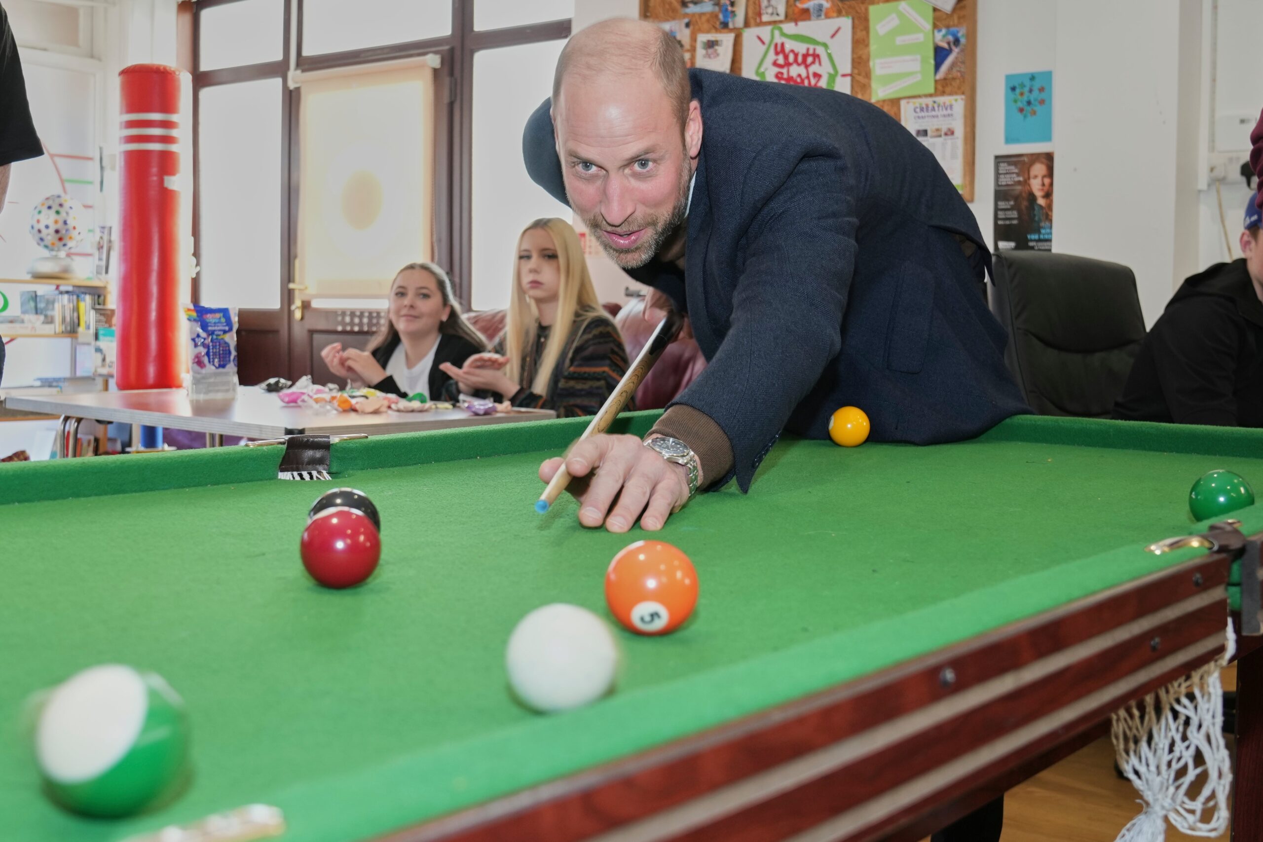 The Prince of Wales plays pool during a visit to Youth Shedz headquarters
