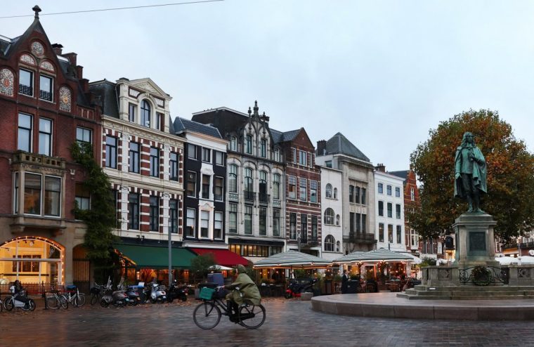 A woman cycles past bars and restaurants in the center of The Hague, Netherlands, November 3, 2025. REUTERS/Piroschka van de Wouw