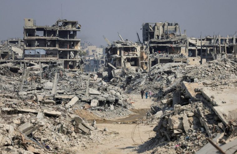 Palestinians walk past destroyed buildings following Israeli military operations in Gaza City, November 7, 2025. REUTERS/Dawoud Abu Alkas