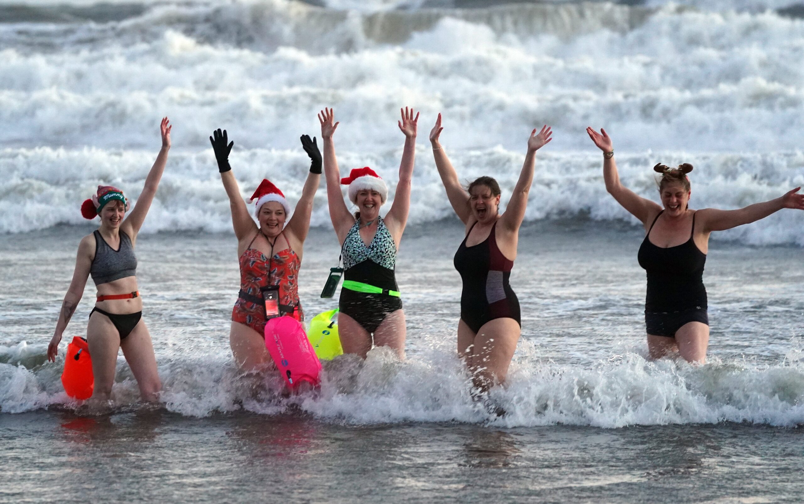 Swimmers go for a Christmas Day dip at Tynemouth beach, north-east England (Owen Humphreys/PA)