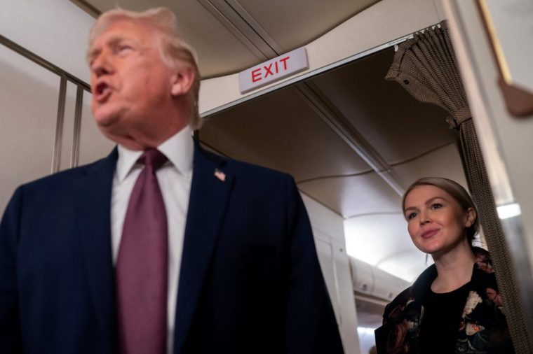 White House Press Secretary Karoline Leavitt listens as U.S. President Donald Trump speaks with members of the media aboard Air Force One en route from Florida to Joint Base Andrews, Maryland, U.S., January 11, 2026. REUTERS/Nathan Howard